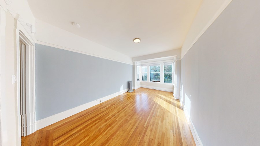 A long hallway with wood floors and white walls.
